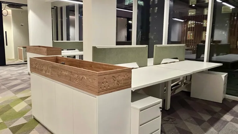 محطات عمل بيضاء بفواصل خضراء، ووحدة تخزين يعلوها حوض نباتات خشبي بنقوش محفورة، تحت إضاءة خطية معلقة